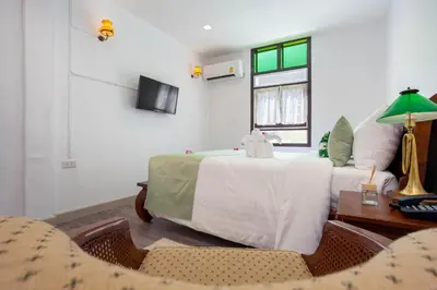 a bedroom with a bed and a table and a window at Sound Gallery House - SHA Plus in Phuket Town