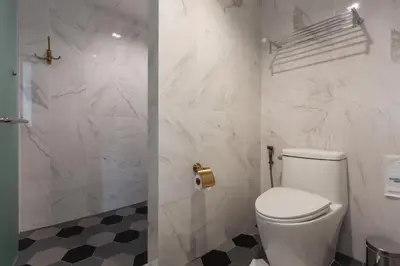 a white bathroom with a toilet and a shower at Sound Gallery House - SHA Plus in Phuket Town