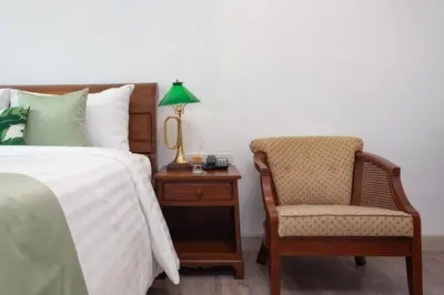 a bedroom with a bed and a chair and a lamp at Sound Gallery House - SHA Plus in Phuket Town