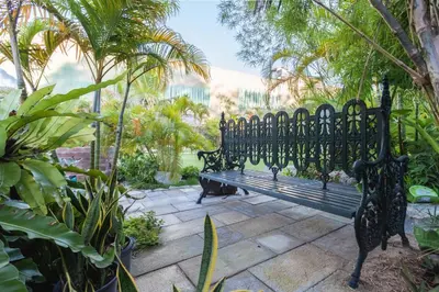 a black bench sitting in the middle of a garden at Sound Gallery House - SHA Plus in Phuket Town