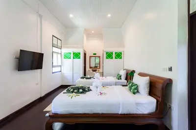 two beds in a room with white walls and a tv at Sound Gallery House - SHA Plus in Phuket Town