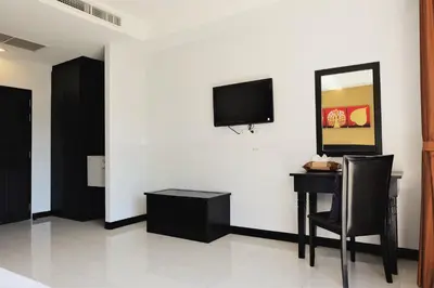 a room with a desk and a tv on a wall at Naiyang Beach Hotel SHA Plus in Nai Yang Beach