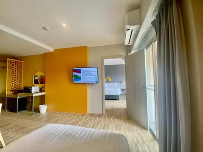 a room with a bed and a tv on a wall at Beehive Boutique Hotel Phuket in Phuket Town