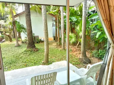 a porch with two chairs and an umbrella at Garden Home Kata in Kata Beach