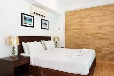 a bedroom with a large bed and a brick wall at Garden Home Kata in Kata Beach