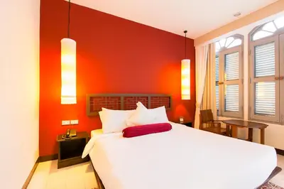 a bedroom with a white bed and red wall at The Memory at On On Hotel in Phuket Town