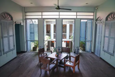 a dining room with a table and chairs and windows at The Memory at On On Hotel in Phuket Town