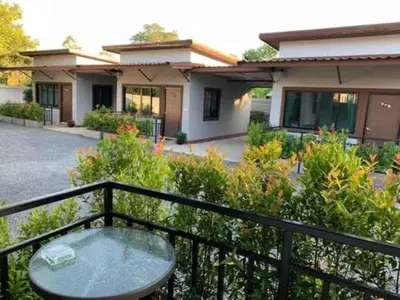 a balcony with a table and a house at Thalang resort in Thalang