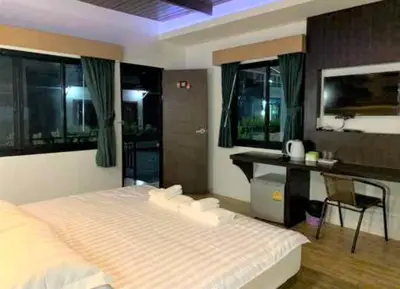 a bedroom with a bed and a desk and windows at Thalang resort in Thalang
