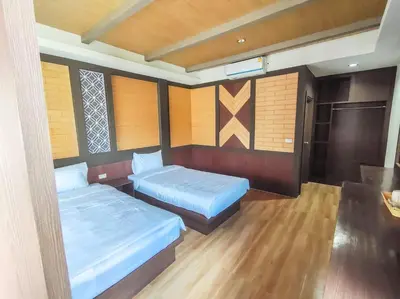 two beds in a room with wooden walls and wood floors at Thalang resort in Thalang