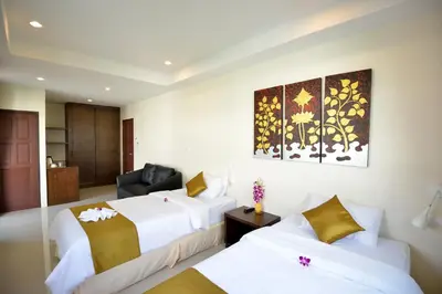 a hotel room with two beds and a chair at At Kamala Hotel in Kamala Beach