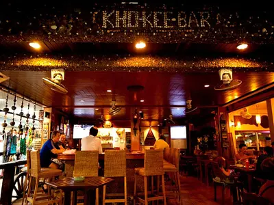 a restaurant with people sitting at a bar at At Kamala Hotel in Kamala Beach