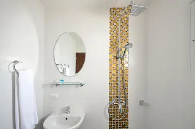 a bathroom with a shower and a sink and a mirror at At Kamala Hotel in Kamala Beach