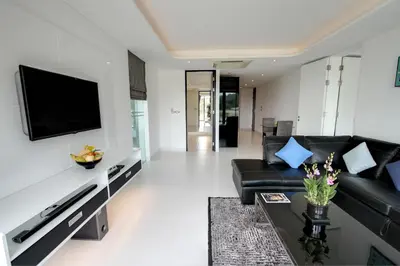 a living room with a black couch and a flat screen tv at Absolute Twin Sands Resort & Spa - SHA Extra Plus in Patong Beach