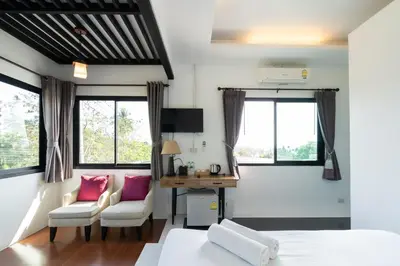 a bedroom with a bed and a desk and windows at The Loft Panwa Resort in Panwa Beach
