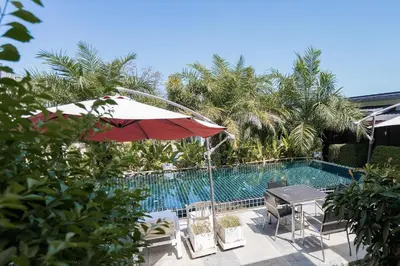 a pool with a table and an umbrella and chairs at The Loft Panwa Resort in Panwa Beach