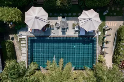an overhead view of a swimming pool with two umbrellas at The Loft Panwa Resort in Panwa Beach
