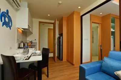 a kitchen and living room with a table and a blue couch at The Aristo Beach by Holy Cow, studio, construction view in Surin Beach