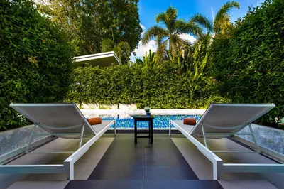 two chairs sitting on a patio next to a pool at The Palmery Resort in Kata Beach