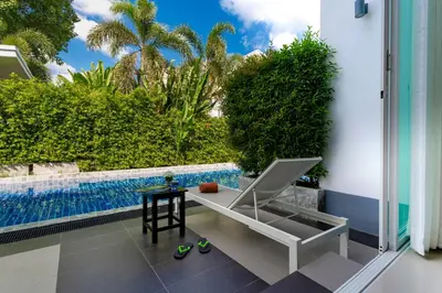 a patio with a chair and a table next to a pool at The Palmery Resort in Kata Beach