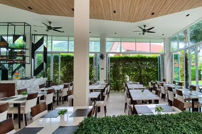 a restaurant with tables and chairs and windows at The Palmery Resort in Kata Beach