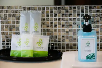 a bottle of hand soap and towels on a tray next to a sink at The Palmery Resort in Kata Beach