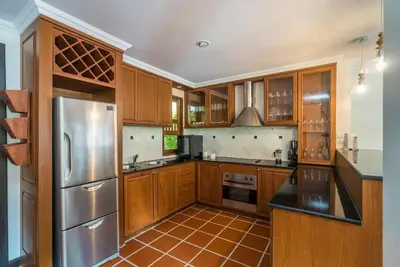 a kitchen with wooden cabinets and a stainless steel refrigerator at Pool villa at Nakatani Village by Lofty in Kamala Beach