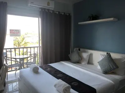 a bedroom with two beds and a balcony with a table at Khao Oat airport in Nai Yang Beach