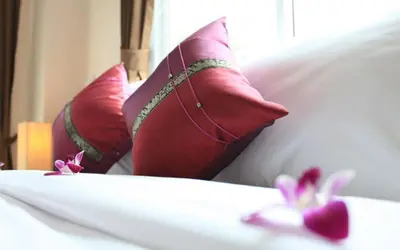 a bed with red pillows and pink flowers on it at 88 Hotel in Patong Beach