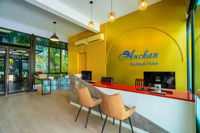 a restaurant with a yellow and red counter with chairs at Anchan Boutique Hotel in Chalong