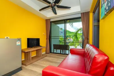 a living room with a red couch and a tv at Anchan Boutique Hotel in Chalong