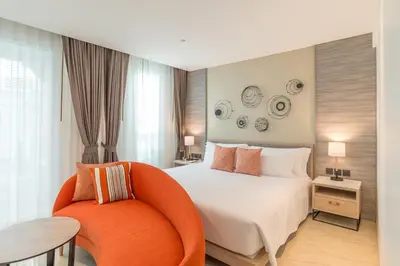 a bedroom with a white bed and an orange chair at Centara Ao Nang Beach Resort & Spa Krabi in Ao Nang Beach