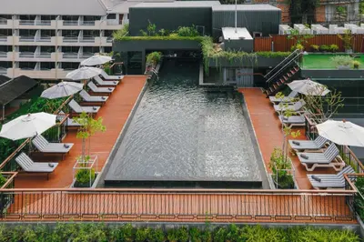 a swimming pool with chairs and umbrellas on a building at Rak Elegant Hotel Patong in Patong Beach