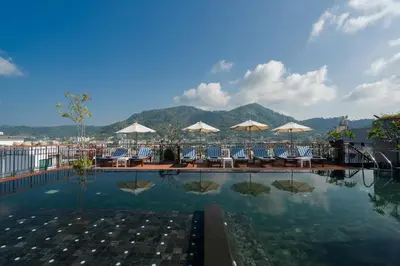 a hotel swimming pool with chairs and umbrellas at Rak Elegant Hotel Patong in Patong Beach
