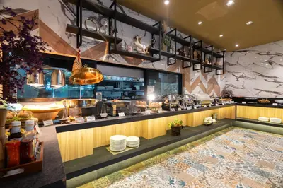a restaurant with a counter with dishes on it at Rak Elegant Hotel Patong in Patong Beach