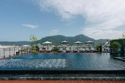 a large swimming pool with chairs and umbrellas at Rak Elegant Hotel Patong in Patong Beach