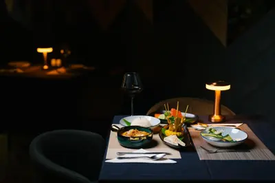 a table with plates of food and a wine glass at Rak Elegant Hotel Patong in Patong Beach