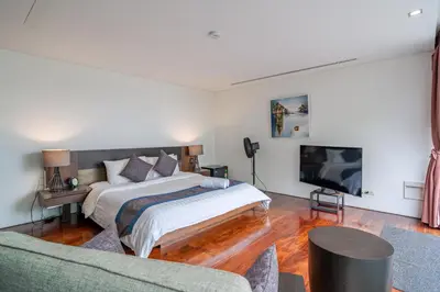 a bedroom with a bed and a tv and a couch at Surin Beach Oceanfront Villa with Ocean and Beach views in Surin Beach