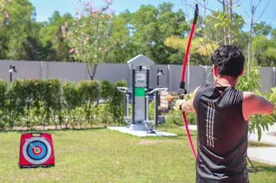 a man holding a bow and arrow in a yard at Anantara Vacation Club Mai Khao Phuket in Mai Khao Beach
