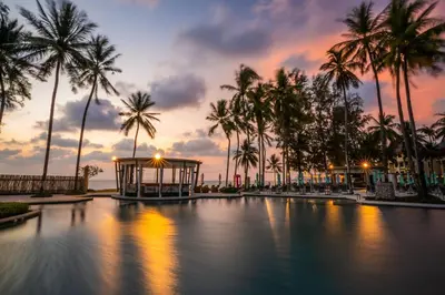a pool with a gazebo and palm trees at sunset at SAii Laguna Phuket in Bang Tao Beach