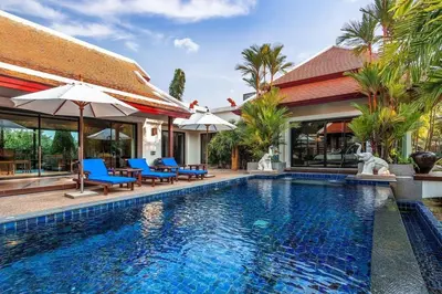 a pool with chairs and umbrellas next to a house at VILLA TOGIAN Private Pool Naiharn beach in Rawai Beach