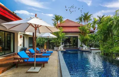 a pool with chairs and an umbrella next to a house at VILLA TOGIAN Private Pool Naiharn beach in Rawai Beach