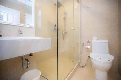 a bathroom with a shower and a toilet and a sink at Baumanburi Hotel Patong in Patong Beach