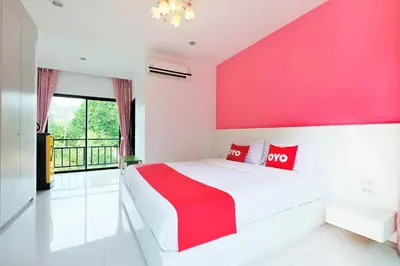 a pink bedroom with a white bed with red pillows at Tina Boutique Resort in Thalang