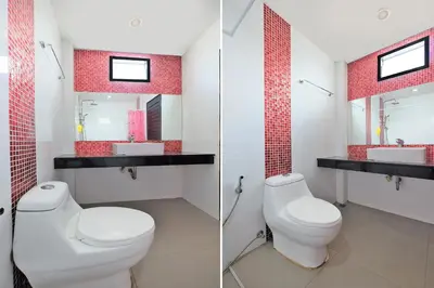 a bathroom with two toilets and a sink and a mirror at Tina Boutique Resort in Thalang