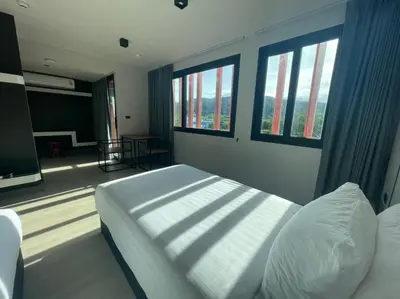 a bedroom with a bed and two windows at PRIME TOWN - Posh & Port Hotel PHUKET in Phuket Town