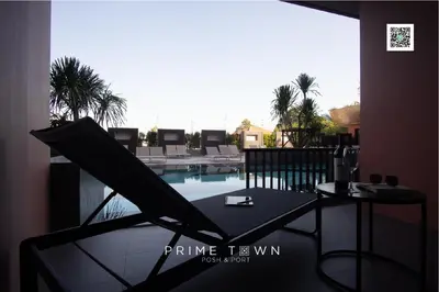 a table and a chair next to a swimming pool at PRIME TOWN - Posh & Port Hotel PHUKET in Phuket Town