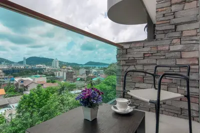 a table with a vase of flowers on a balcony at Emerald Terrace Resort in Patong Beach