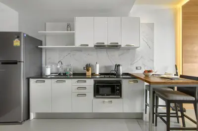 a kitchen with white cabinets and a black refrigerator at Emerald Terrace Resort in Patong Beach