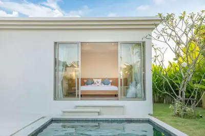 a house with a pool and a bed in the window at Trichada Tropical in Bang Tao Beach